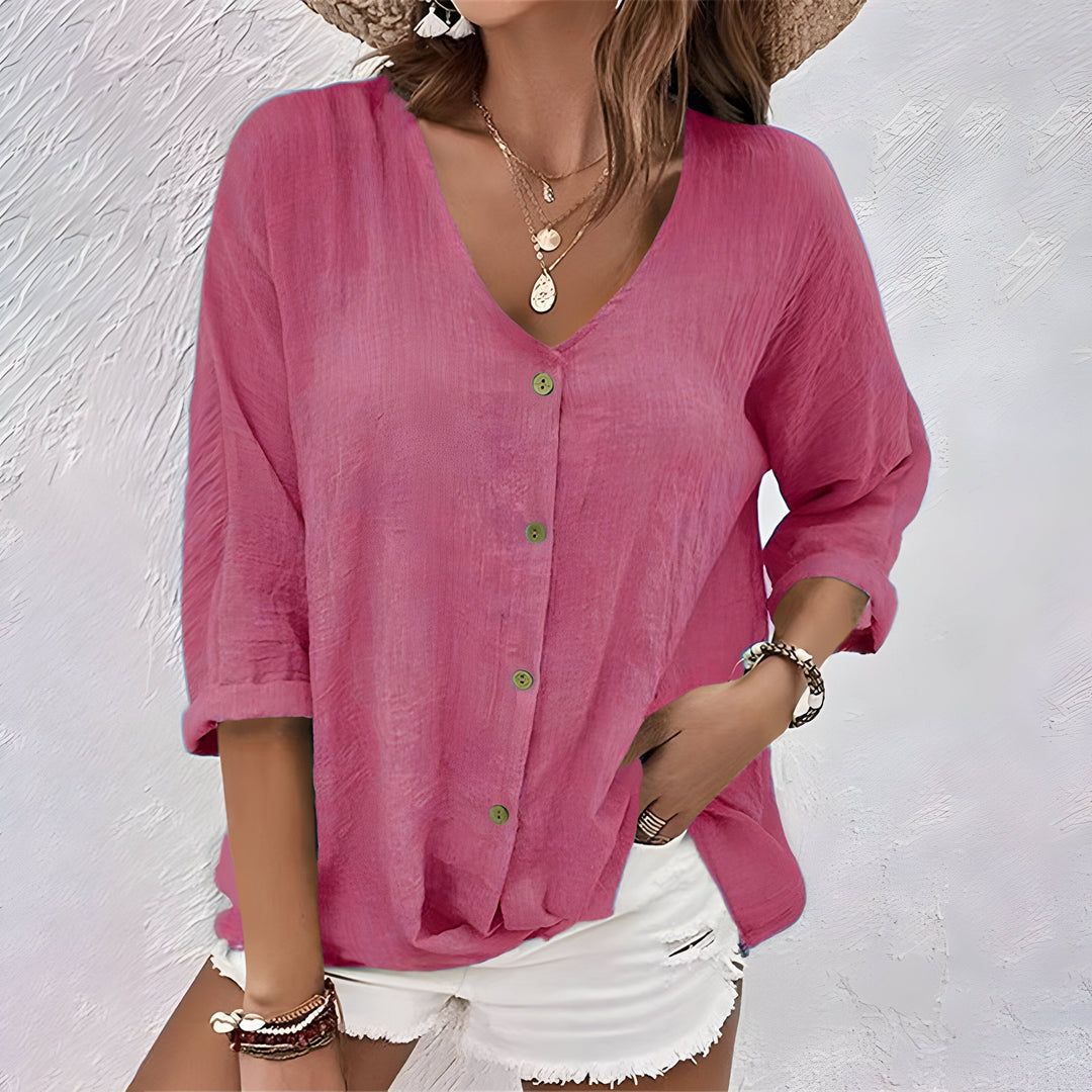 Pink linen-look V-neck blouse with a button-up front and relaxed fit, styled with white shorts.