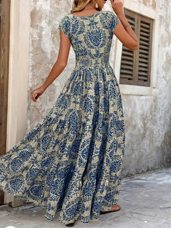 Boho maxi dress with a blue floral print, smocked bodice, cap sleeves, and a flowing tiered skirt.