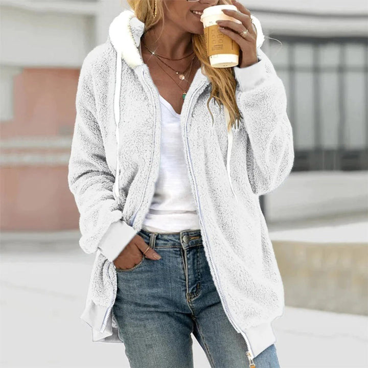 White hooded fleece zip jacket with a relaxed fit, ribbed cuffs, and drawstring hood worn over a white top and blue jeans.